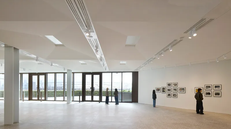Gallery space with polished concrete floor and visitors viewing framed photographs along white walls