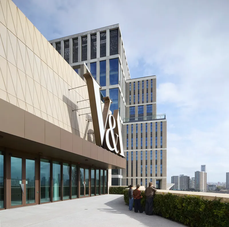 Rooftop terrace with planted beds and visitors gathering near the glazed facade