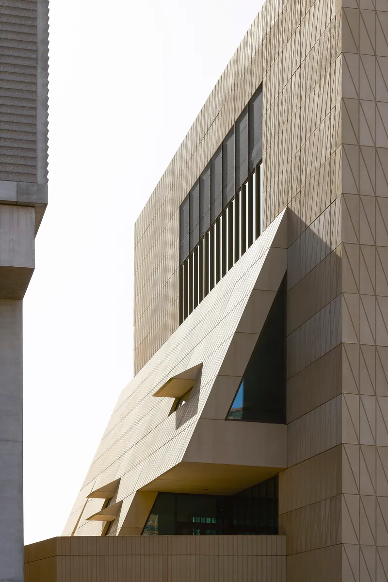 Close-up of the faceted cladding with vertical louvred window opening and projecting balcony