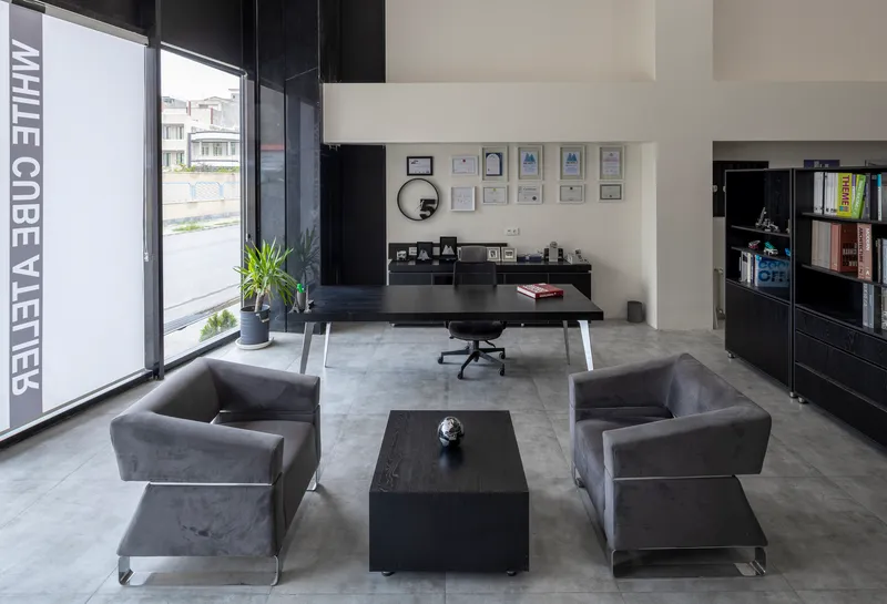 Reception area with grey upholstered chairs and black furniture beneath full-height glazing with lettering