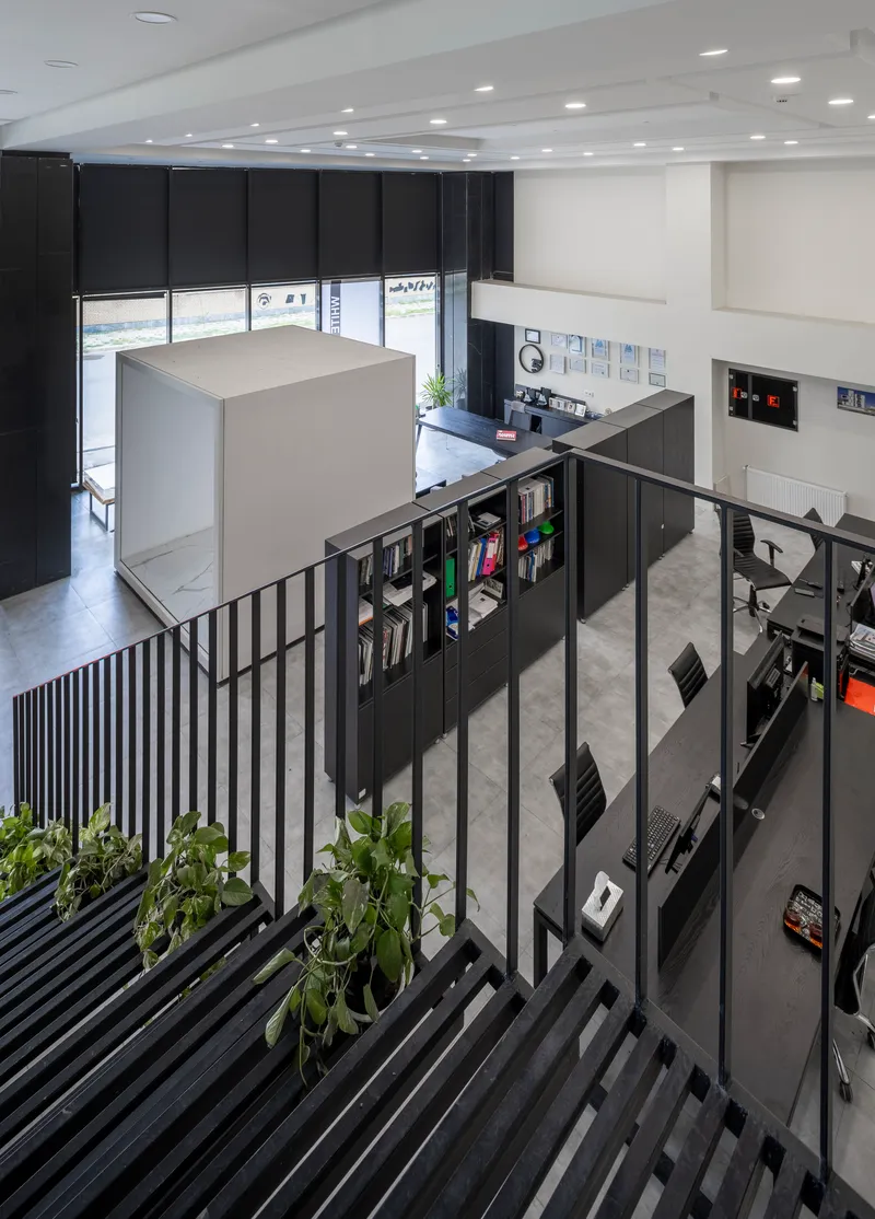 View down the steel staircase with planted treads overlooking the double-height library space with black shelving