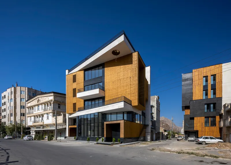 Corner facade showing alternating brick cladding and white horizontal bands with glazed ground floor