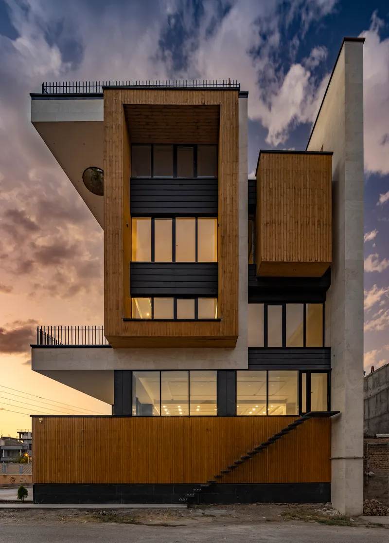 Rear facade with timber cladding and dark metal panels illuminated at dusk