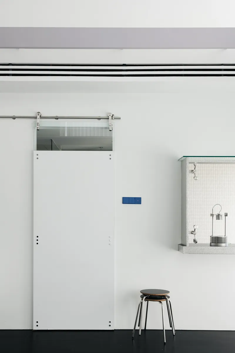 Sliding barn door on exposed track beside a small kitchen pass-through with tile backsplash
