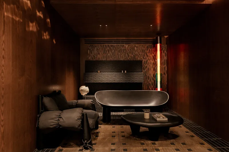Dark timber-clad spa room with an oval soaking tub and chequered floor tiles under ambient lighting