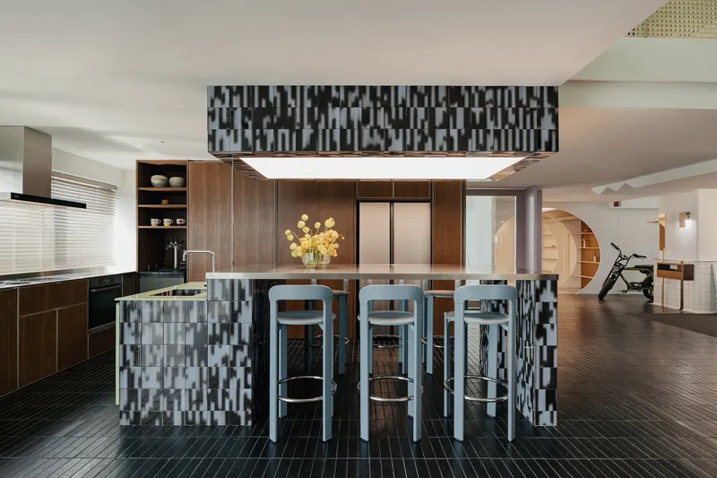 Kitchen island with seating beneath a chequered pendant light in an open plan interior