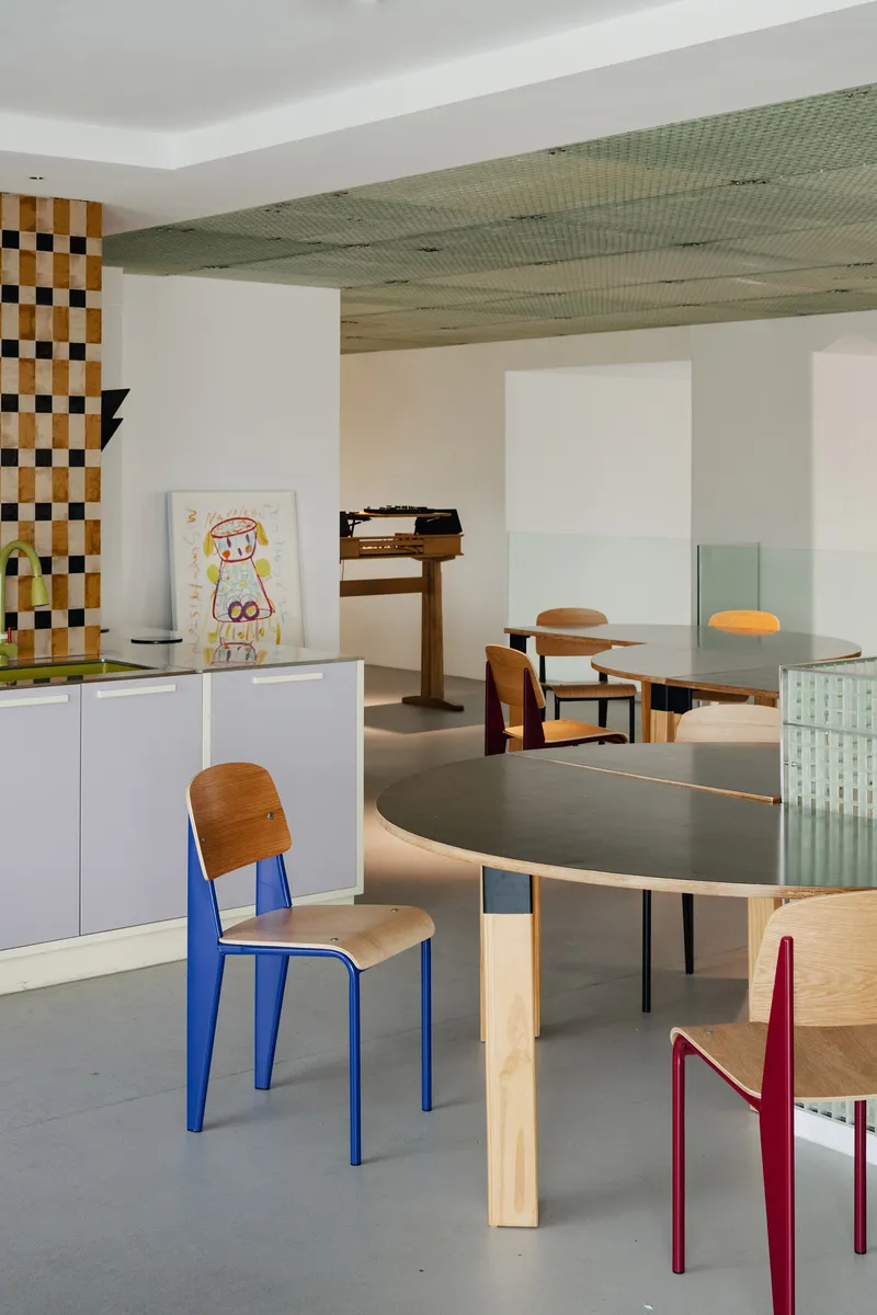Open dining space with checkered tile column and perforated green metal ceiling panels overhead
