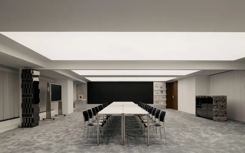 Conference room with long white table beneath continuous skylight and textured column wrapped in dark tiles