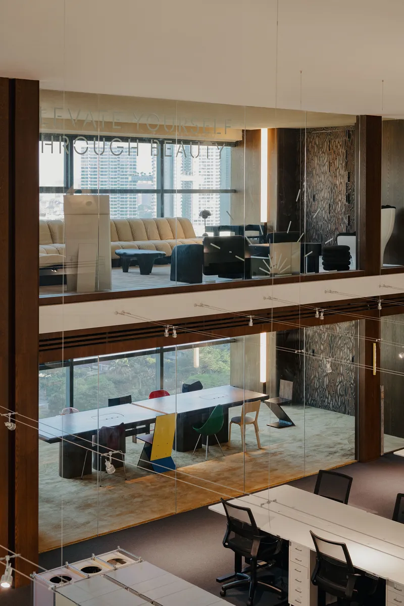 Vertical view through glass-enclosed meeting rooms stacked across three levels with timber framing and textured wall panels