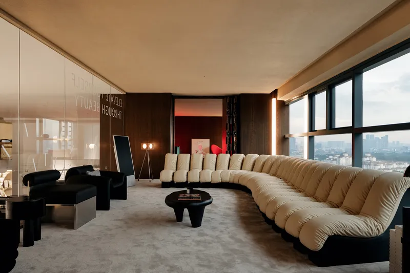 Corner living room with curved sectional sofa, dark timber paneling, and panoramic city views through full-height glazing