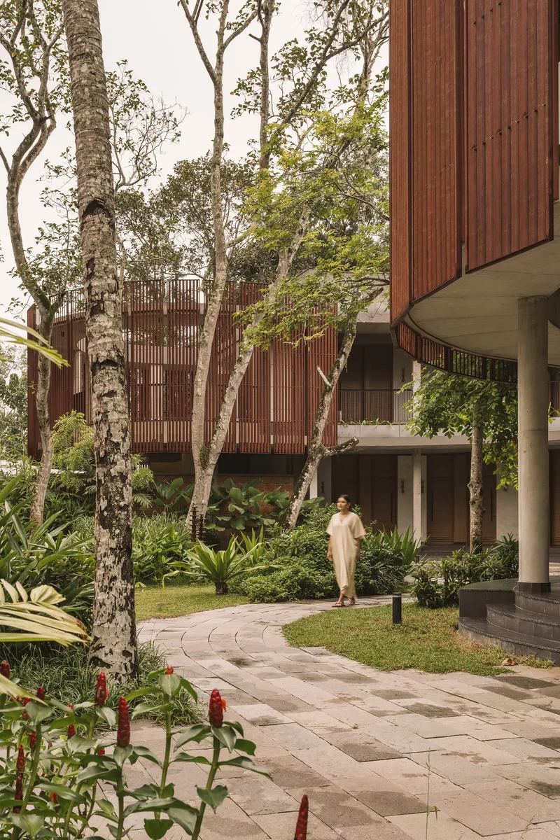 Stone paver pathway through a garden courtyard with existing trees and vertical timber screening above