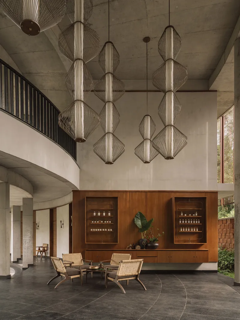 Double-height living space with woven pendant lights suspended above a timber credenza and curved stair