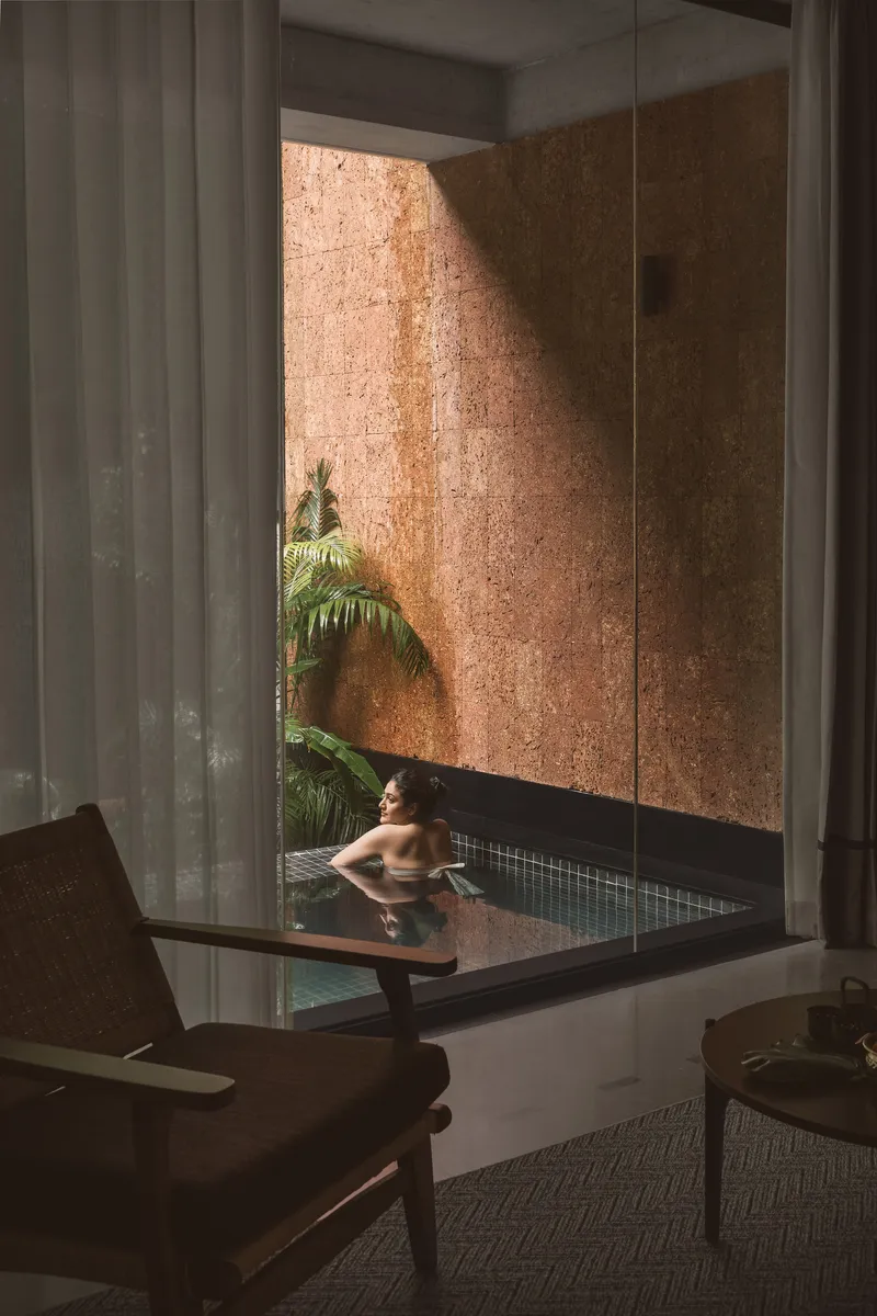 Interior view of a plunge pool with cork-clad walls and a palm tree reflected in still water