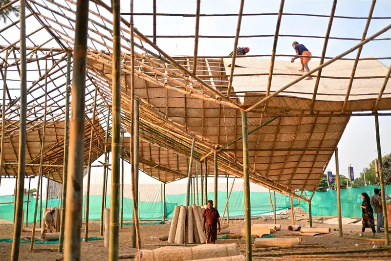 Construction view of bamboo grid roof structures supported by slender columns with workers on top