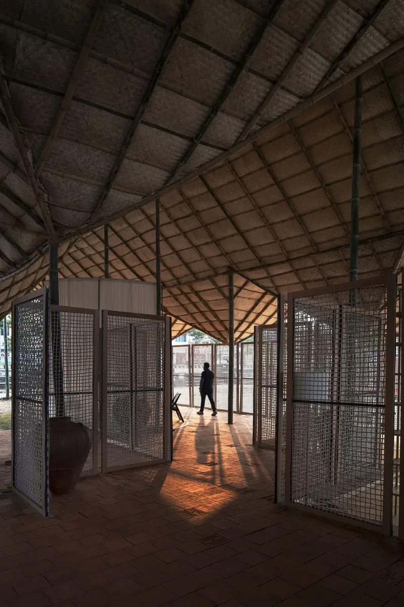 Interior corridor with perforated metal screens and exposed timber trusses filtering afternoon sunlight