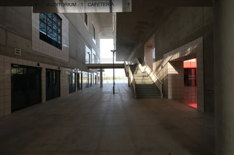 Interior lobby with central staircase and directional signage under concrete vaults with afternoon light