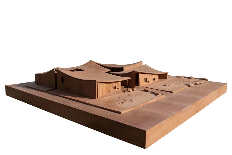 Physical model showing curving roof volumes and stepped courtyard spaces carved into a timber base