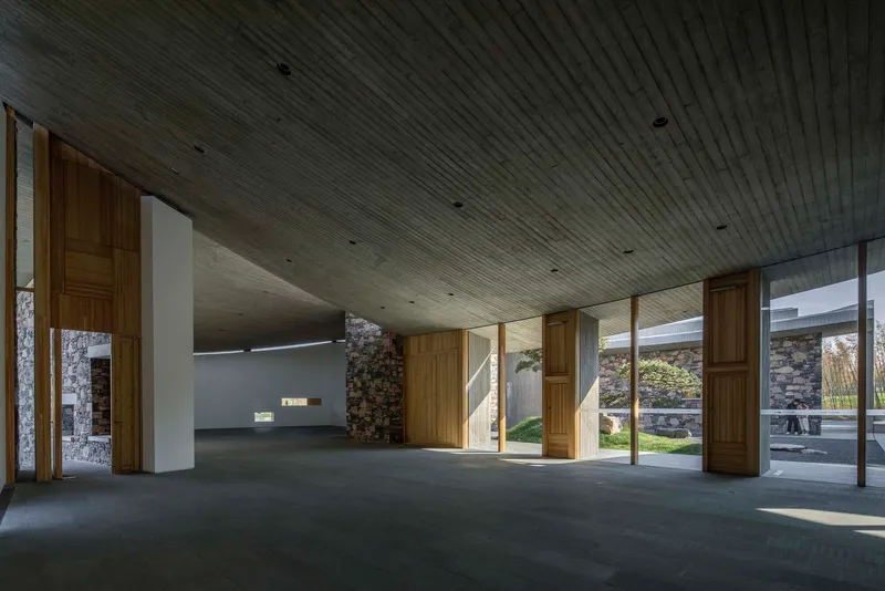 Interior space with board-formed concrete ceiling and pivoting timber doors opening to the courtyard garden