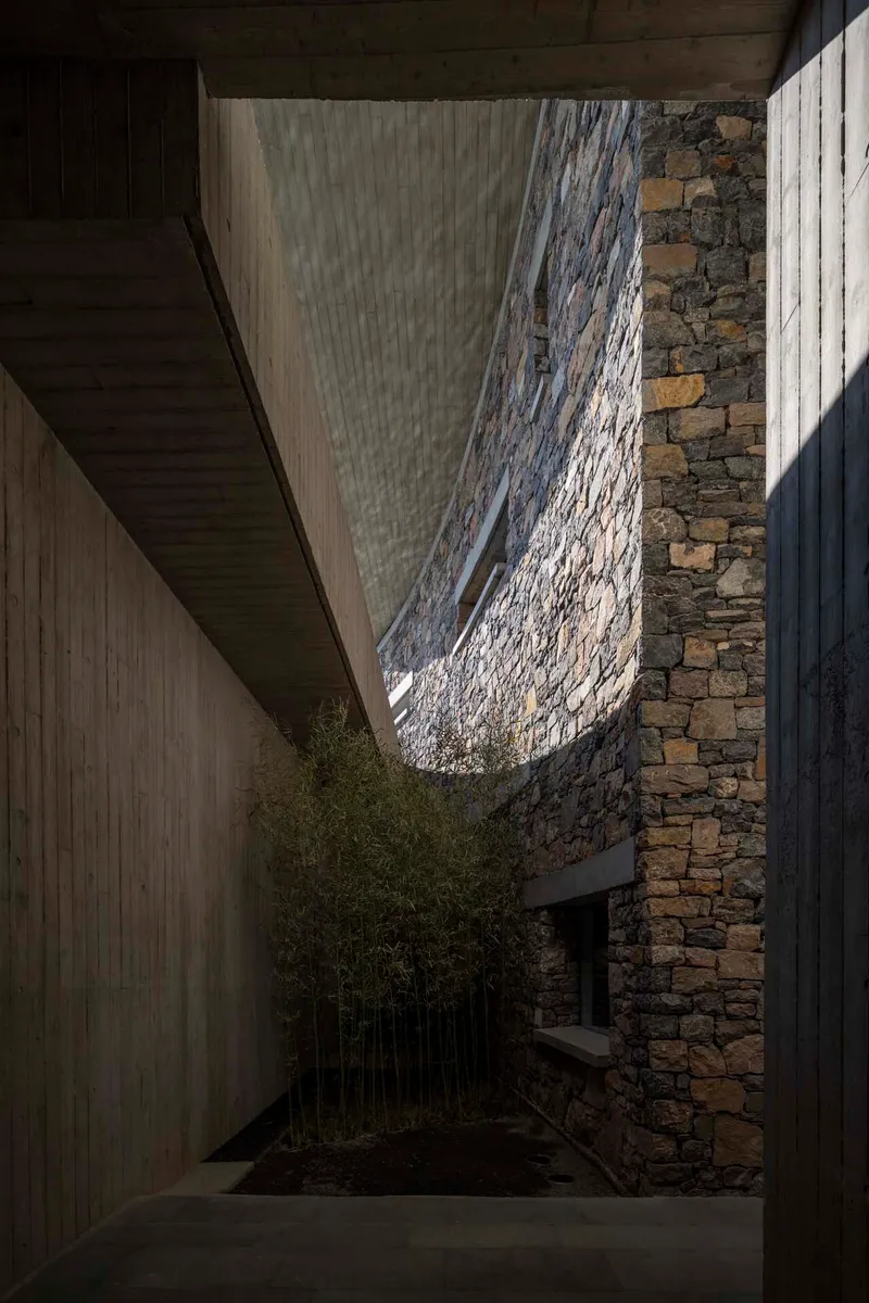 Courtyard view looking up through a curved opening in the stone wall with bamboo below