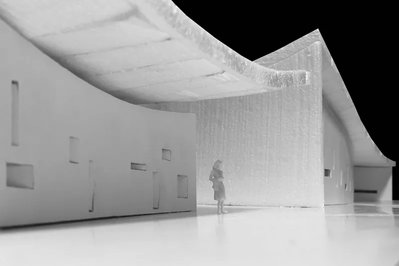 Physical model interior showing a figure beneath curved ceiling volumes and a textured wall