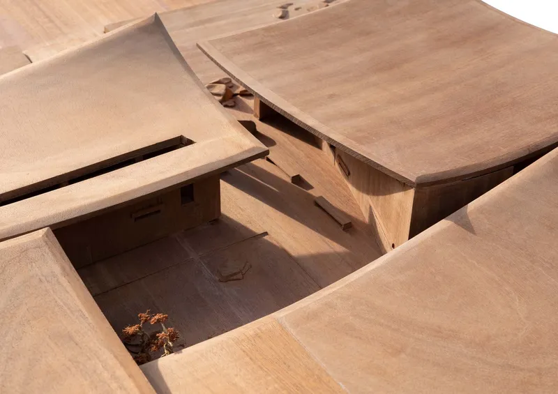 Physical model showing intersecting roof planes and a sunken courtyard with a small tree