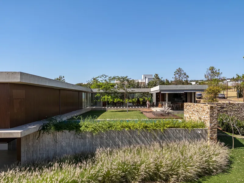 Planted terrace with board-formed concrete retaining wall and grasses overlooking the courtyard and timber volumes