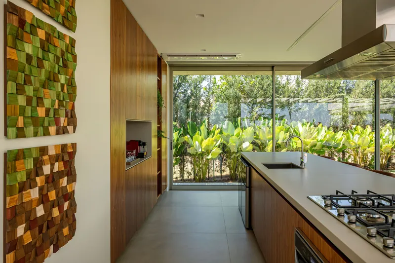 Galley kitchen with textured tile wall and glass doors facing dense plantings of tropical foliage