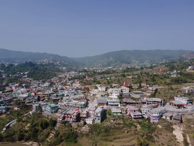 Distant view of a hillside settlement with a red temple tower rising above mixed construction buildings