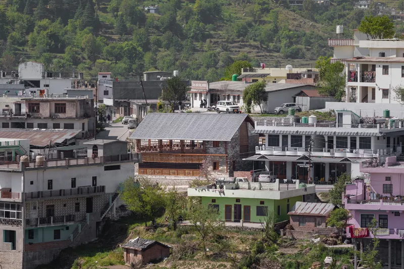 Mid-distance view of a timber and stone two-story house among surrounding concrete residential buildings