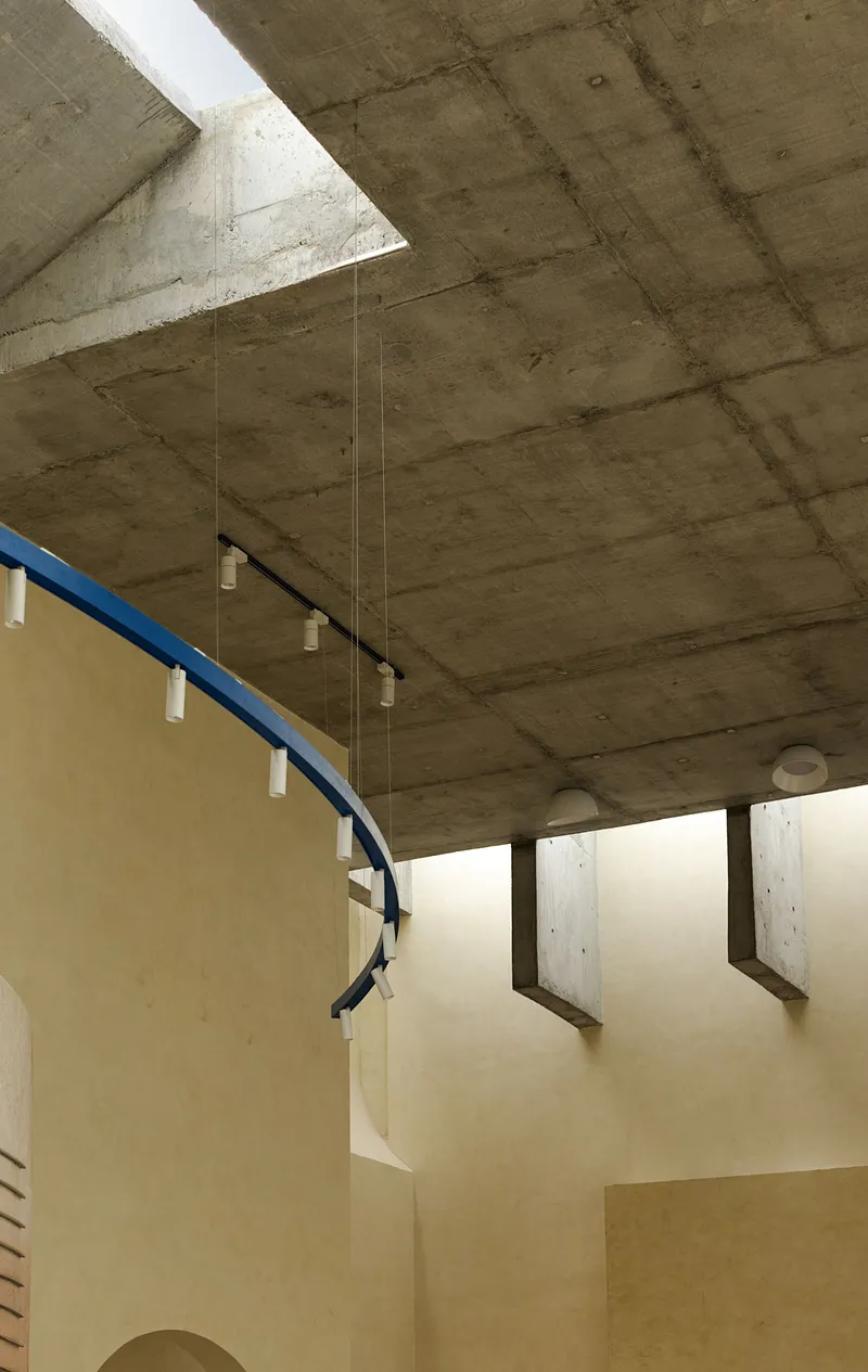 Upward view of the exposed concrete soffit with triangular skylight and blue metal handrail