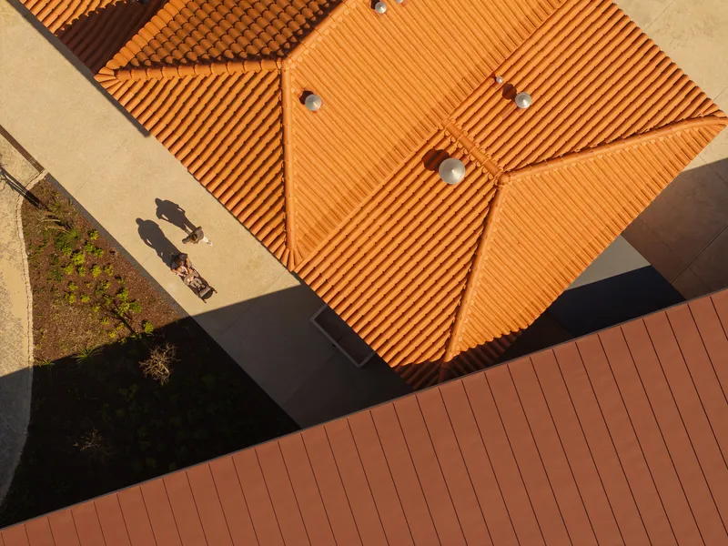 Aerial view of tile rooftops with two visitors casting shadows on paved terrace