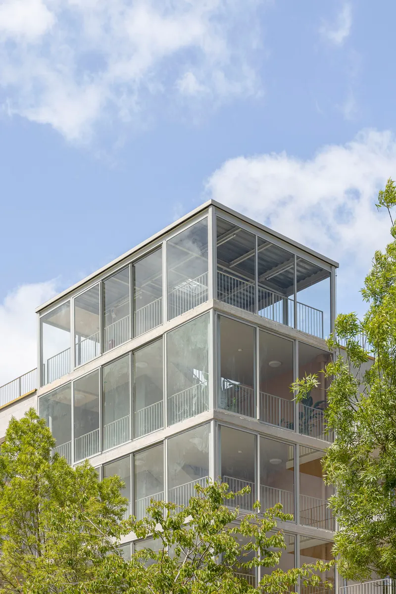 Upper floors of the glazed balcony stack with exposed ceiling slabs visible through transparent panels
