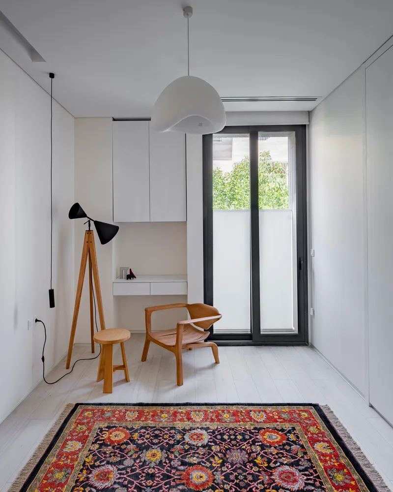 Study nook with built-in desk and timber chair beneath spherical pendant and tripod floor lamp