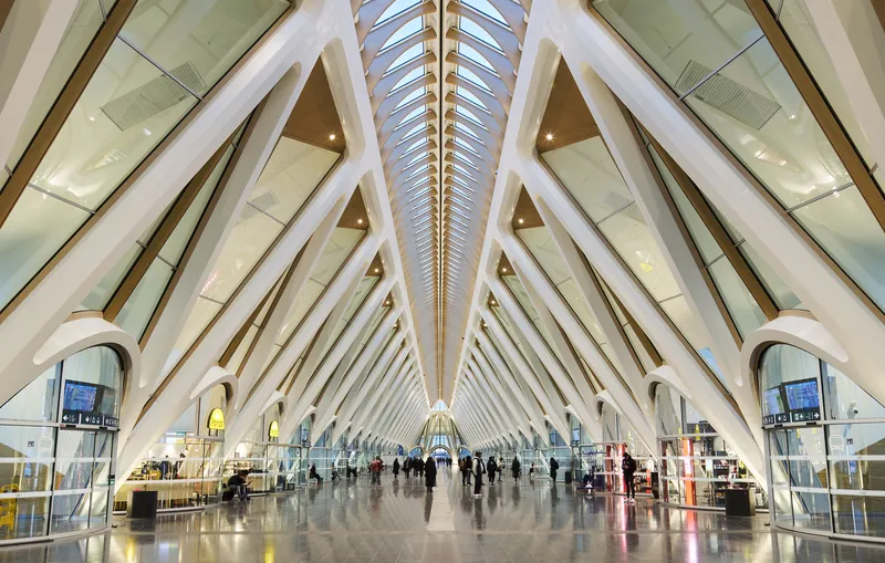 Interior concourse with radiating white arched ribs and central skylight above passengers