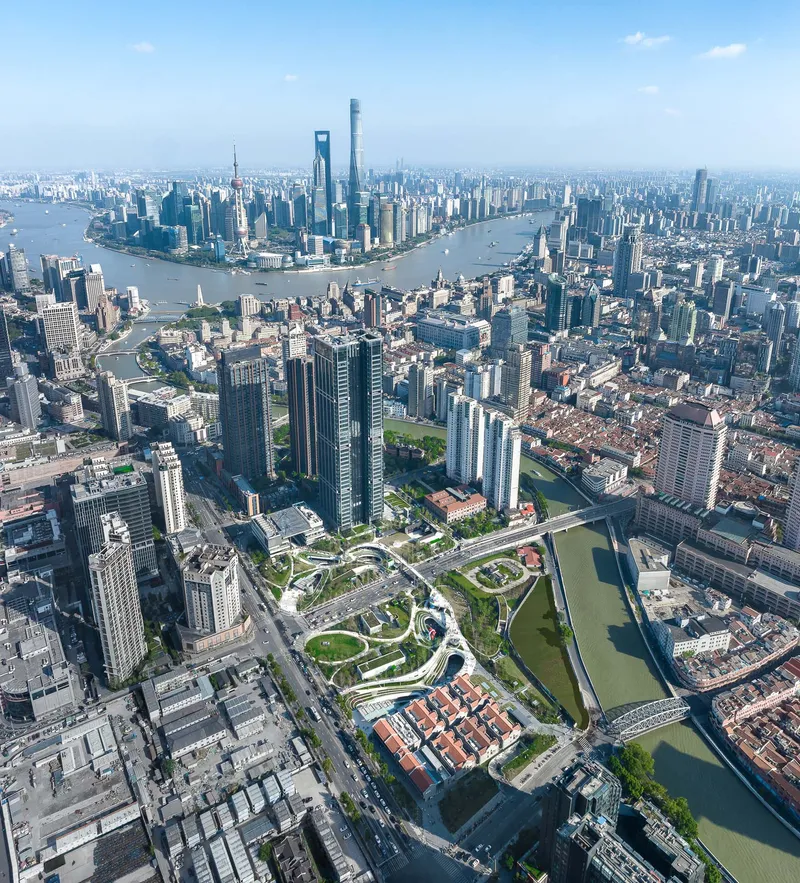 Aerial view of the winding green pathways set among high-rise towers and the river bend