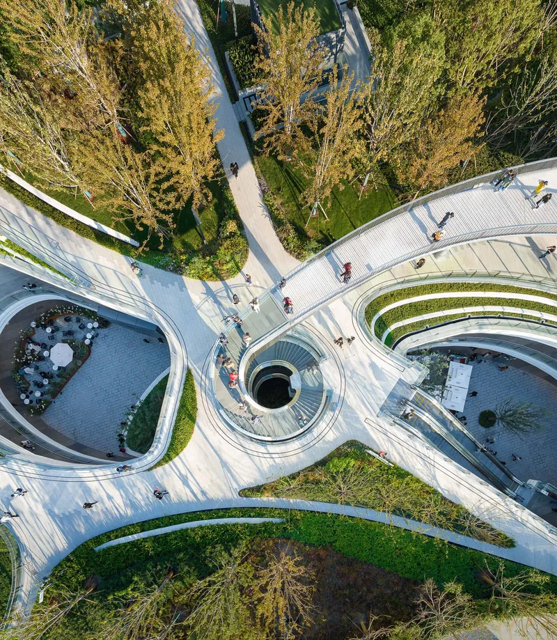 Top-down view of concentric planted terraces radiating from a central circular skylight opening