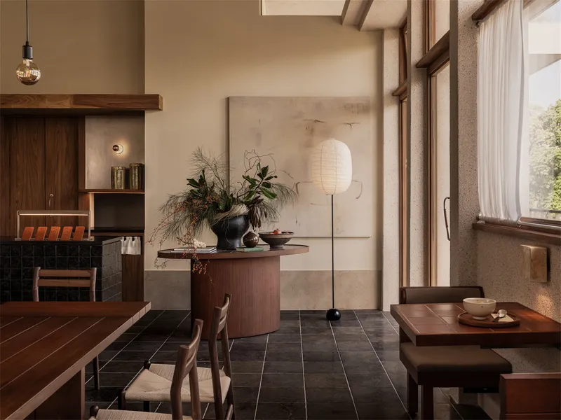 Dining space with timber ceiling beams, tall window, and paper lantern beside floral arrangement