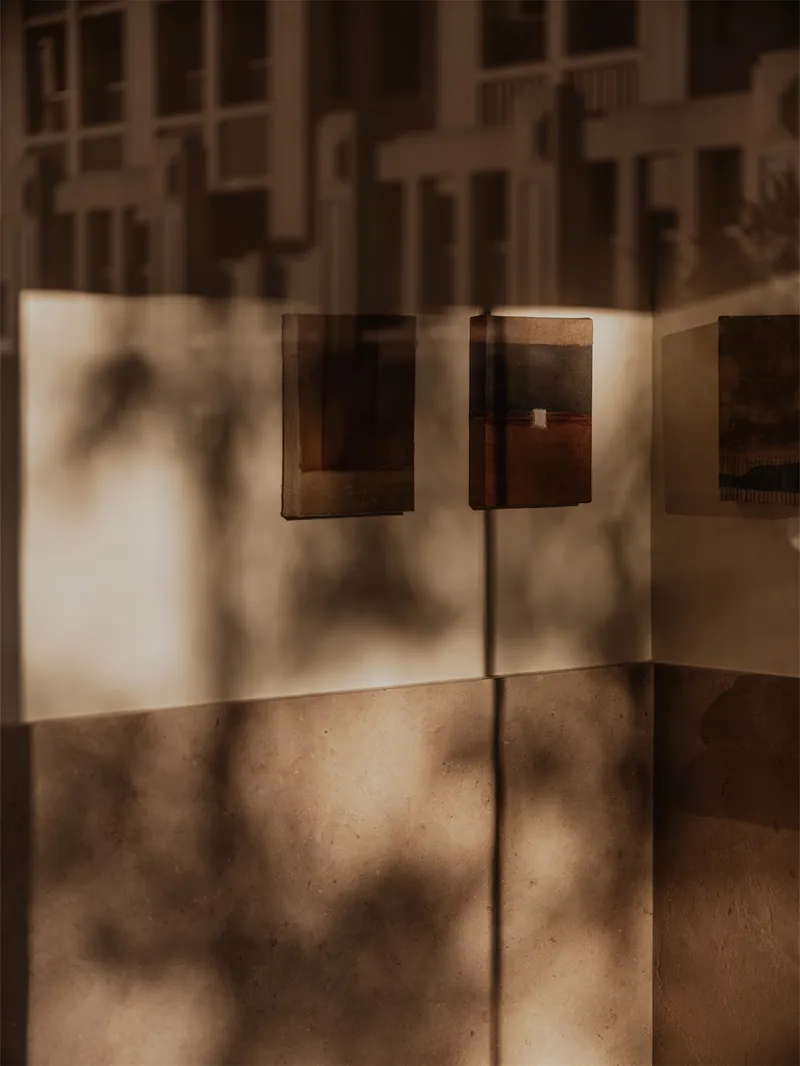 Close-up of brass wall sconces casting shadows on terrazzo floor in diffused sunlight