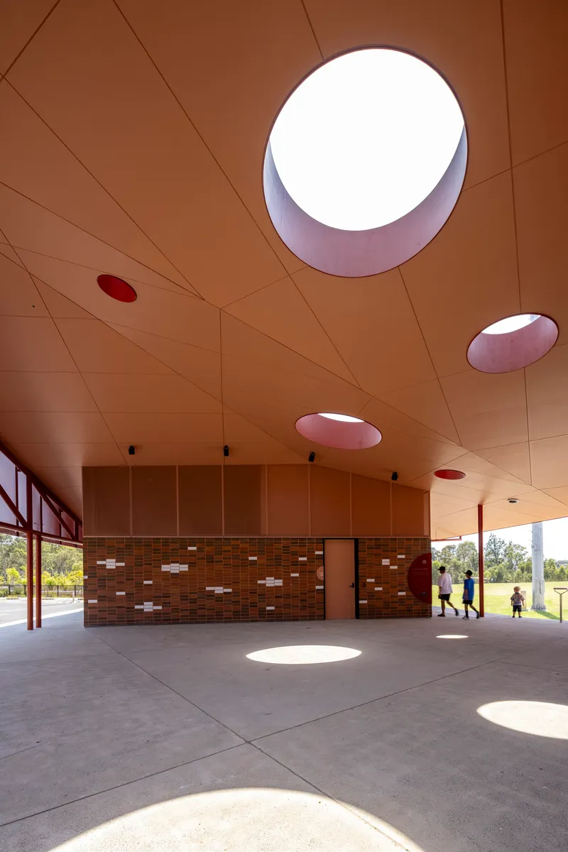 Covered breezeway with circular skylights casting round shadows on the concrete floor below