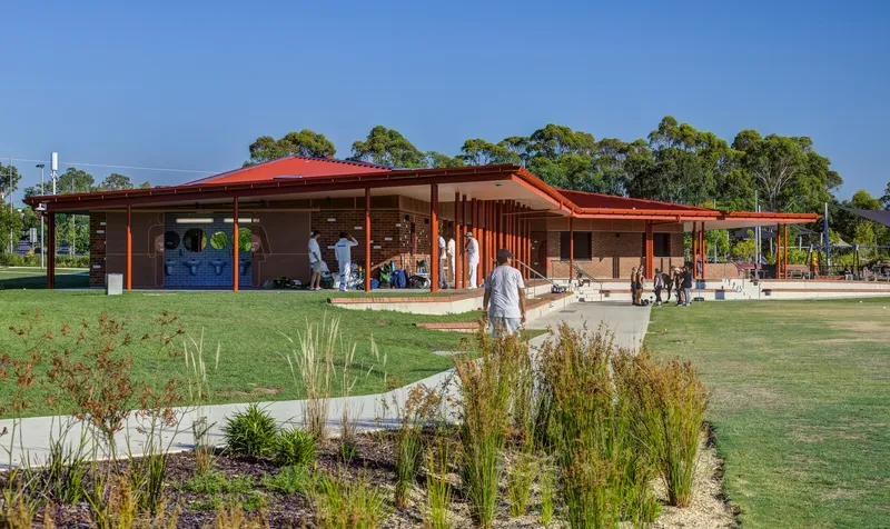 Garden approach with native grasses in the foreground and families walking beneath the wide eaves