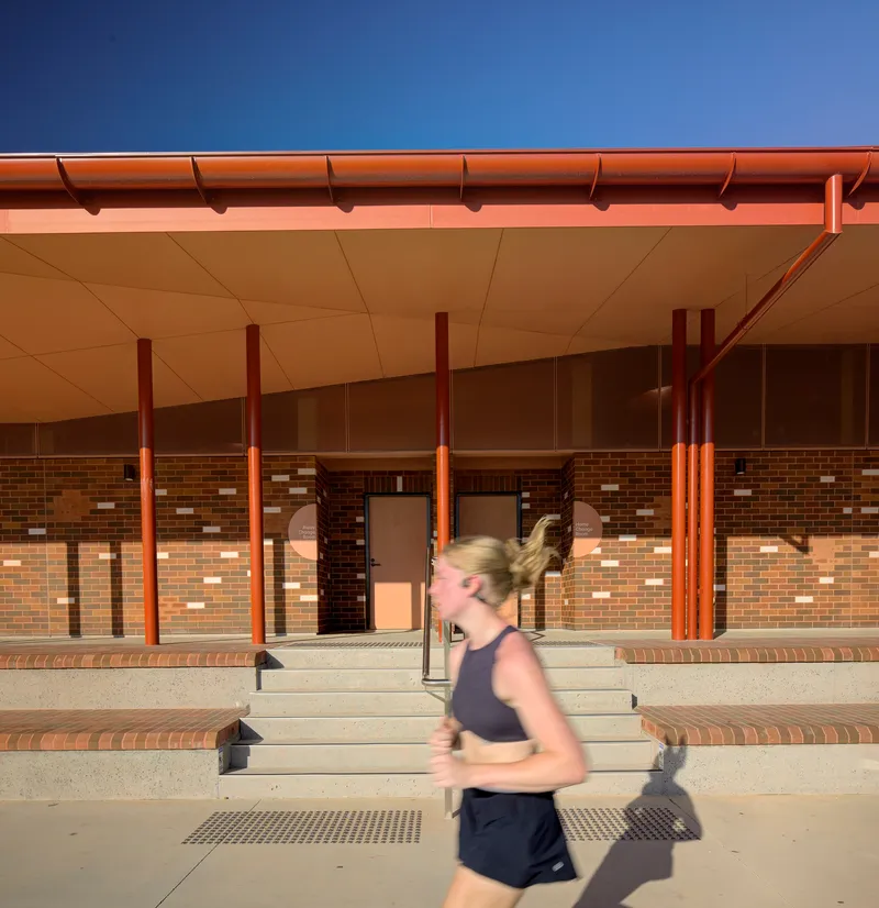 Stepped concrete entry with blurred runner passing under the red eave and gutter at dusk