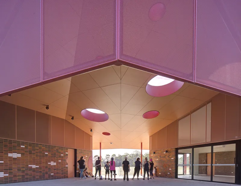 Interior gathering space with visitors silhouetted beneath vaulted ceiling with circular purple skylights