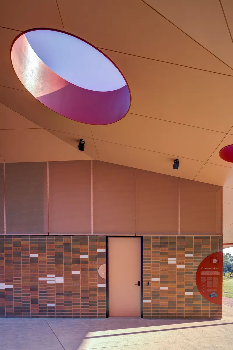 Single oval skylight with purple rim casting colored light onto the timber ceiling panels