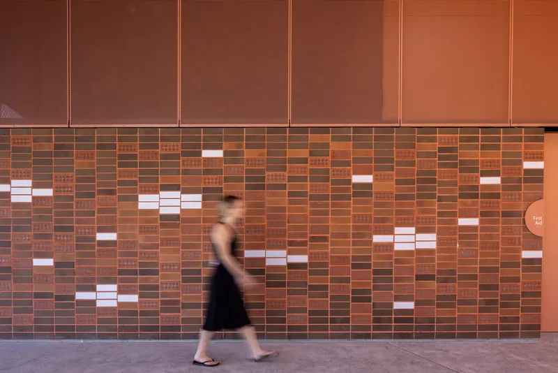 Patterned brick wall with scattered white ceramic tiles as a person walks past in motion blur