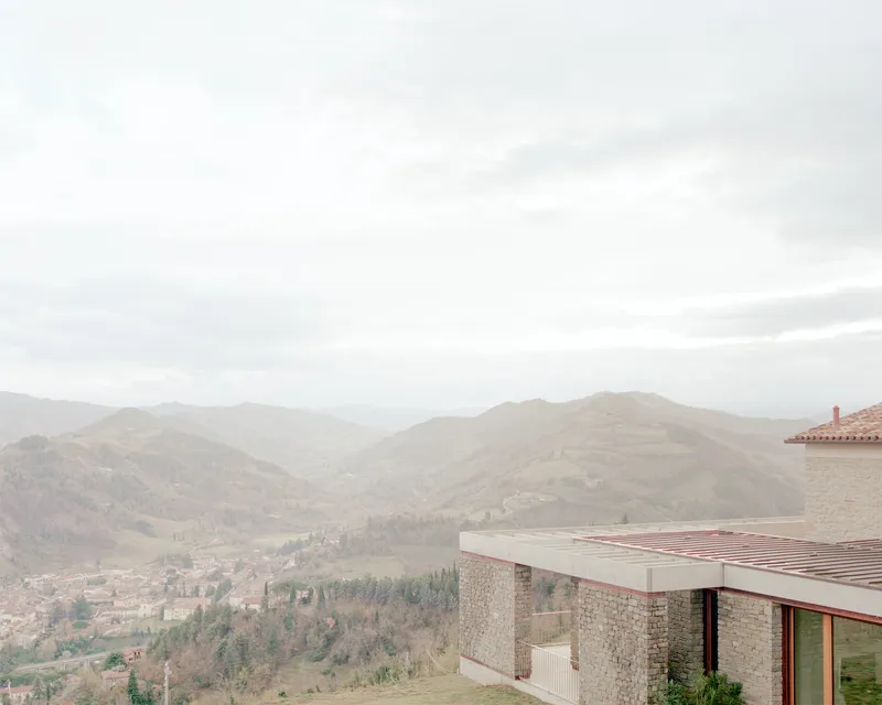 Flat roof terrace with timber battens overlooking a valley of distant hills in hazy light