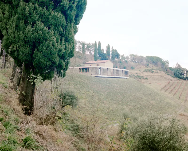 Distant view of the linear volume nestled among rolling hills and cypress trees in winter