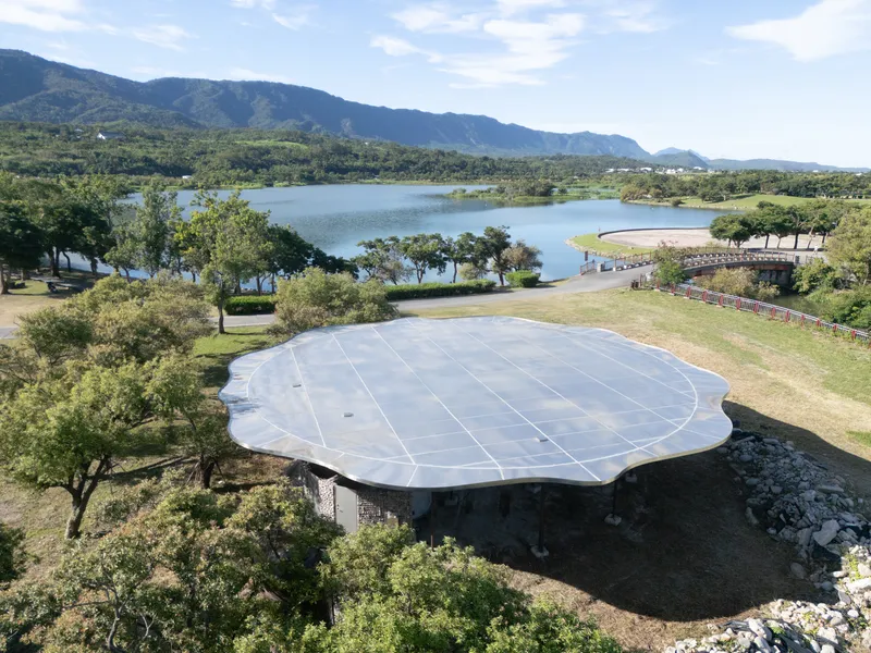 Top-down view of the paneled metallic roof overlooking a lake with mountains in the distance