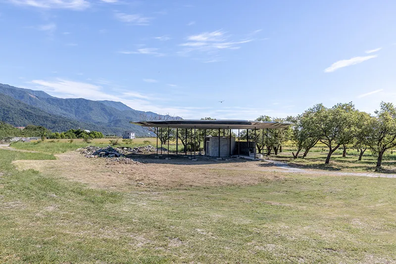 Long view of the pavilion roof in open grassland with mountain range beyond