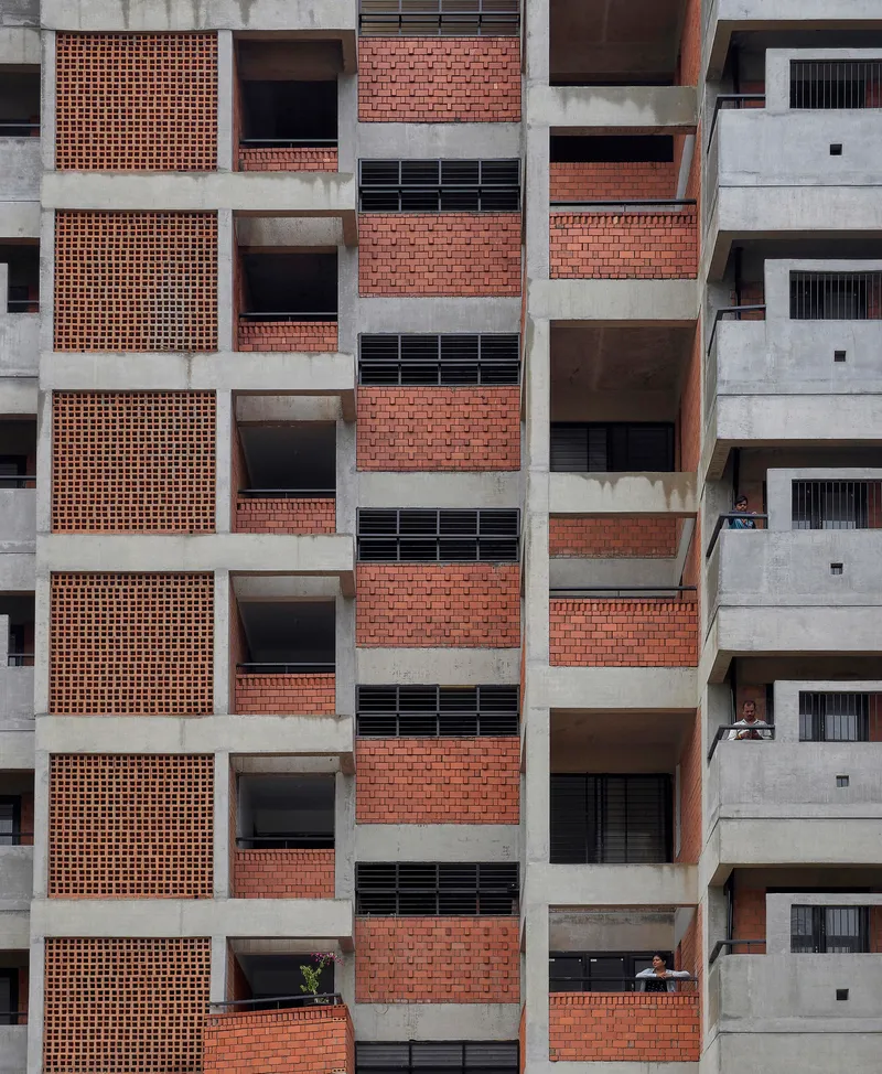 Facade elevation showing alternating concrete frames with perforated brick screens and recessed balconies