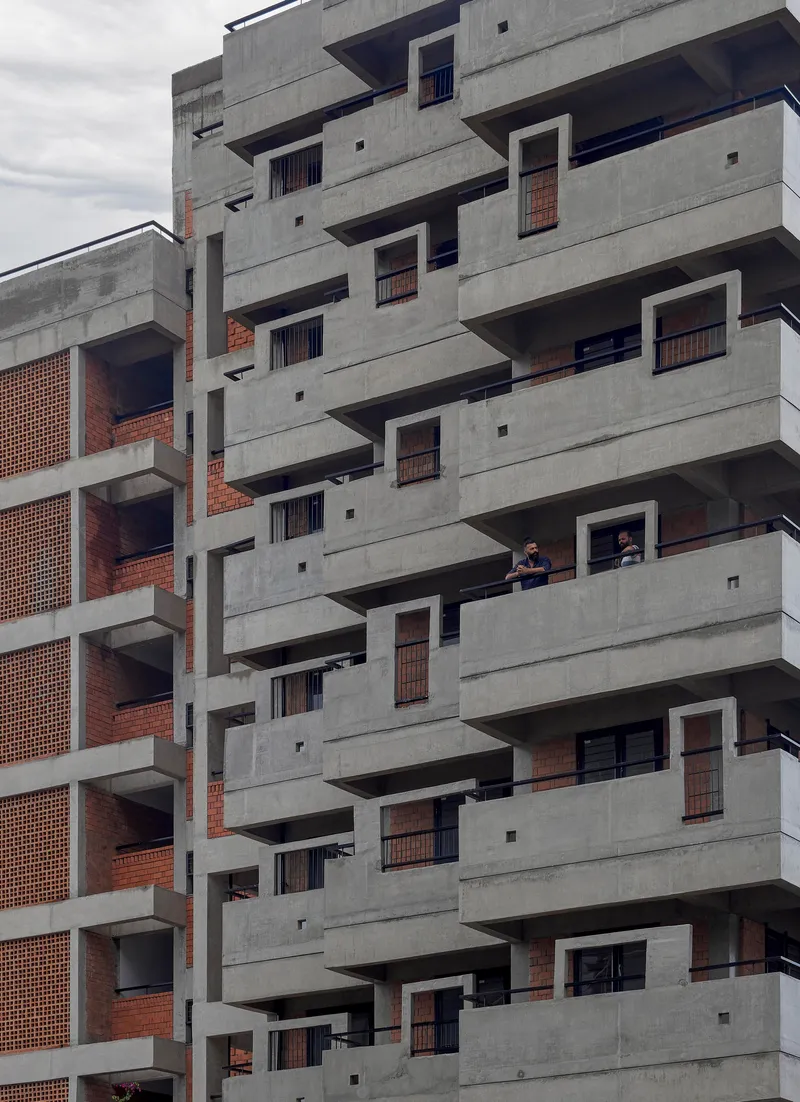 Stepped concrete balconies with brick screening and residents visible on one of the terraces